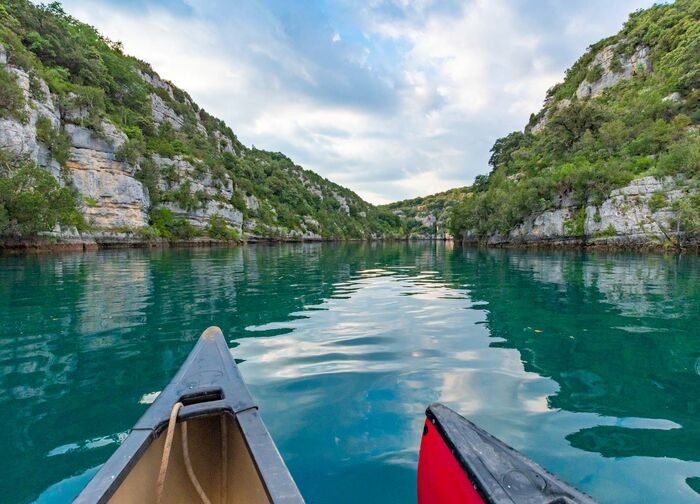 Vue depuis un canoë sur les eaux turquoise des gorges du Verdon, entourées de falaises verdoyantes, proche du camping Le Clos de Barbey